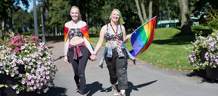 två unga kvinnor hand i hand på Pride